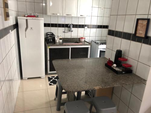 a small kitchen with a table and a refrigerator at A Passos da Areia Apartamento 2 Quartos no Coração da Badalada Praia do Morro - WiFi Fibra in Guarapari