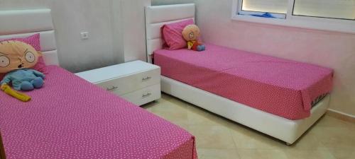 two beds in a bedroom with pink sheets at Appartement meublé Unica 2 Fes in Fez