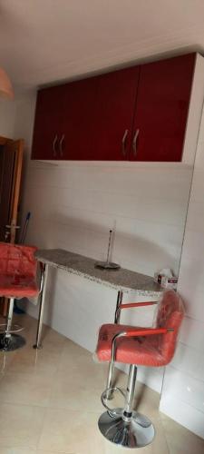 une cuisine avec un bar et une chaise rouge à un comptoir dans l'établissement Appartement meublé Unica 2 Fes, à Fès
