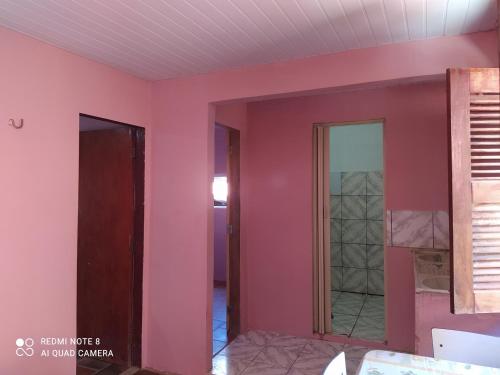 Habitación con paredes rosas y puerta de cristal. en Suítes D'Belinha, en Canoa Quebrada
