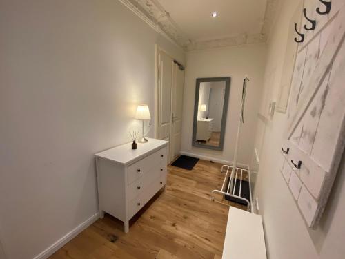 Cette chambre comprend une commode blanche et un miroir. dans l'établissement Ferienwohnung Lipsia, à Leipzig