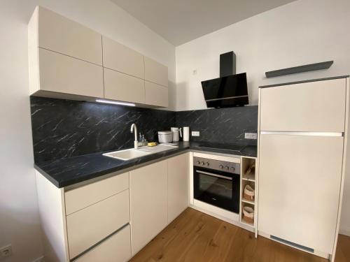 a kitchen with white cabinets and a sink and a refrigerator at Ferienwohnung Lipsia in Leipzig