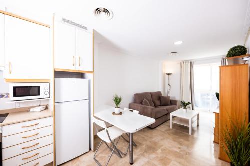 cocina y sala de estar con mesa y sofá en Apartamentos Turísticos Alba, en Cartagena