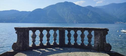 a stone bench sitting on the edge of a body of water at Casa Milla in Tremezzo