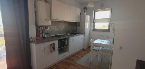 a kitchen with white cabinets and a table and a window at Welcome In(n) Central Pitești in Piteşti