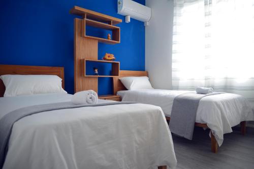 2 camas en una habitación con paredes azules en Mahebourg Family Home, en Mahébourg