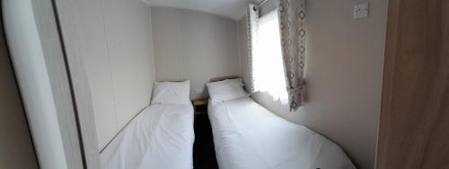 2 camas blancas en una habitación con ventana en Lake view en Newquay