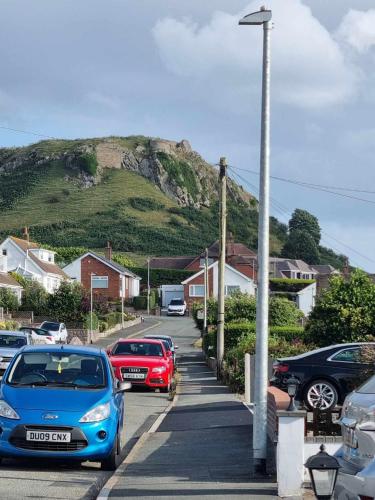 a bunch of cars parked in a parking lot with a mountain at Ann's Garden flat in Deganwy
