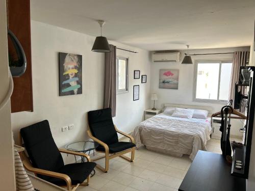 a bedroom with a bed and two chairs at Amir's Apartments in Tel Aviv