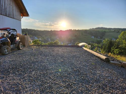 a golf cart parked on the side of a building with the sunset at Apartament u Ewki in Rdzawka