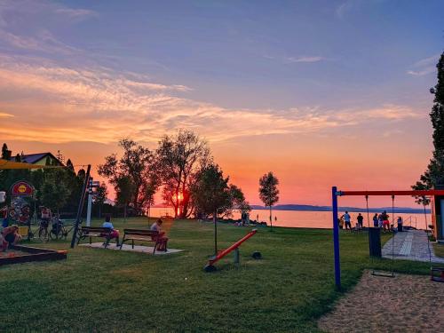 un parque con gente sentada en bancos y un parque infantil en Molnár Vendégház en Balatonboglár