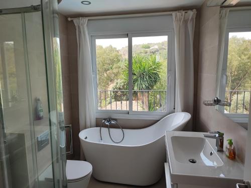 ein Bad mit einer Badewanne, einem WC und einem Fenster in der Unterkunft Penthouse Apartment, Cortijo Fruitful HIlls in Málaga
