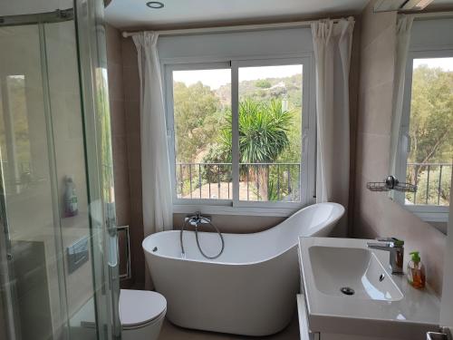 a bathroom with a tub and a toilet and a window at Penthouse Apartment, Cortijo Fruitful HIlls in Málaga