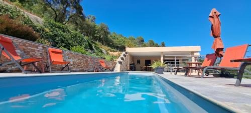 a swimming pool with chairs and a house at Les Hauts du Peireguier in La Motte