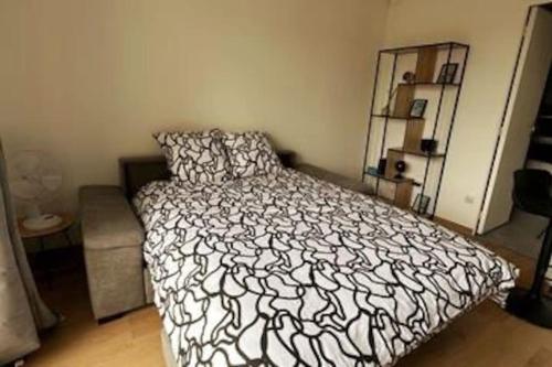 ein Schlafzimmer mit einem Bett mit einer schwarz-weißen Bettdecke in der Unterkunft L'escale, Studio proche Gare Melun avec parking privé in Dammarie-les-Lys