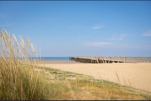 une plage de sable avec une jetée et l'océan dans l'établissement Studette à 100m de la plage, à Saint-Jean-de-Monts