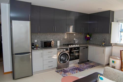 una cucina con armadi neri e una lavatrice/asciugatrice di Cantinho do Rio a Ponte da Barca