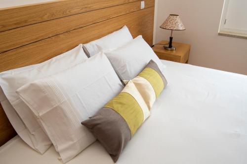 - un lit blanc avec des oreillers blancs et une tête de lit en bois dans l'établissement Cantinho do Rio, à Ponte da Barca