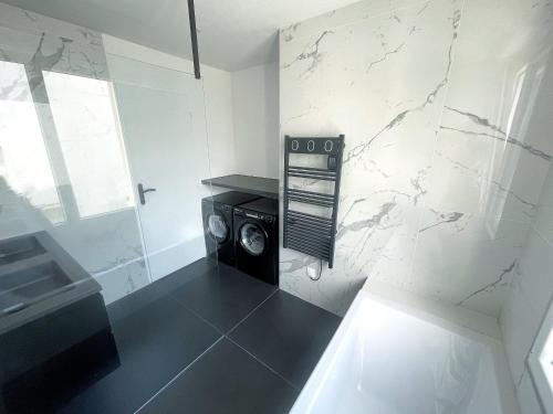 - une salle de bains pourvue d'un lave-linge dans l'établissement Les appartements du Carnot - Terrasses et Jardins, à La Rochelle