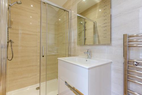 La salle de bains est pourvue d'un lavabo et d'une douche. dans l'établissement The Lion Gate Mews, à Kingston upon Thames