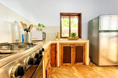 a kitchen with a stainless steel refrigerator and wooden cabinets at Kibanda Natural Kendwa Villa in Kendwa