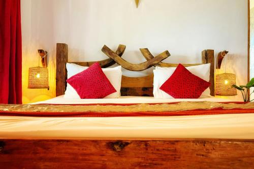 a bed with four red pillows on it at Kibanda Natural Kendwa Villa in Kendwa