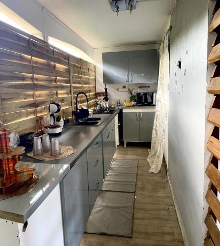 uma cozinha com balcões de aço inoxidável e um lavatório em La suite parentale em Basse-Terre
