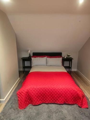 a bed with a red comforter in a room at Ruby Residences in Foots Cray