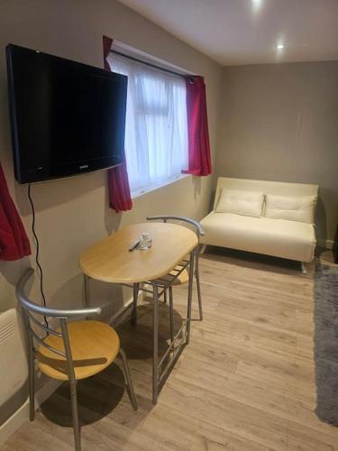 a room with a table and a tv and a couch at Ruby Residences in Foots Cray