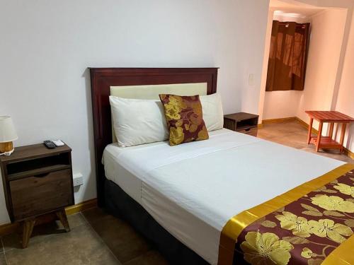a bedroom with a large bed and a night stand at Hotel Amayal in Puerto Iguazú