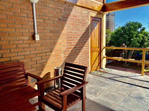 a wooden chair sitting on a porch with a brick wall at Hotel Amayal in Puerto Iguazú