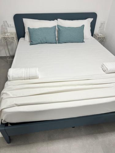 un grande letto con lenzuola bianche e cuscini blu di Cisternone Suites a Formia