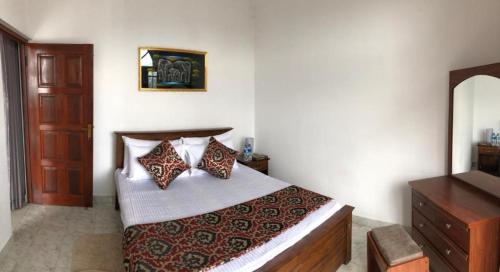 a bedroom with a bed with pillows and a dresser at sands villa in Kandy
