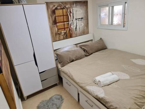 יחידת דיור (חדר וחצי) - גינה פרטית, חנייה חופשית ! في هرتسليا: غرفة نوم صغيرة بها سرير ونافذة