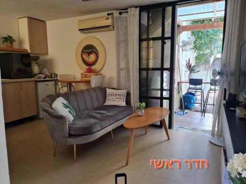 a living room with a couch and a table at יחידת דיור (חדר וחצי) - גינה פרטית, חנייה חופשית ! in Herzliya