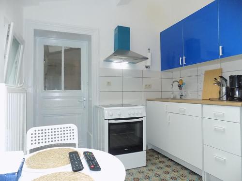 - une cuisine blanche avec des placards bleus, une table et une table dans l'établissement Maison LYDIE - Meublé de vacances 3 étoiles, à Charleroi