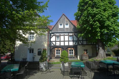 uma casa velha com mesas e cadeiras em frente em Hotel U Zeleného Stromu - Zum Grünen Baum em Hřensko