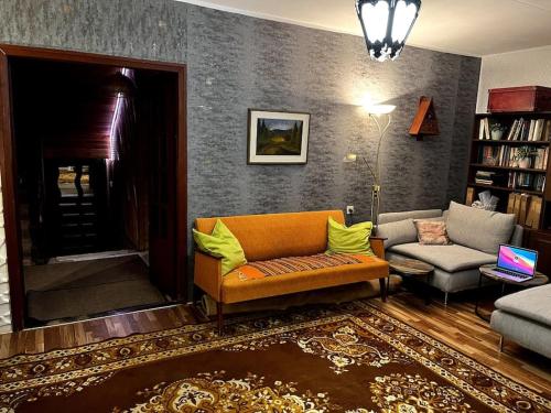 ein Wohnzimmer mit einem orangenen Sofa und einem Stuhl in der Unterkunft Cosy house with forest view in Pyussi