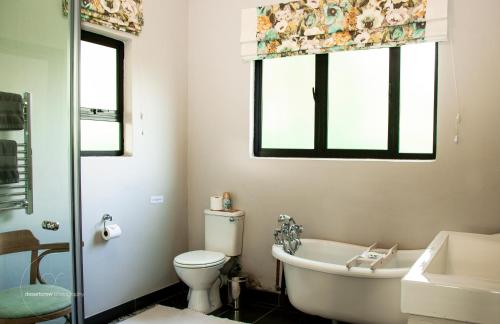 baño con bañera, aseo y ventana en Newstead Farm, en Curryʼs Post