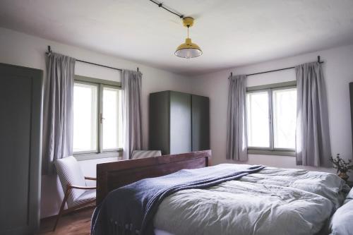 a bedroom with a bed and a chair and windows at Chaloupka Na Gruni in Hrádek