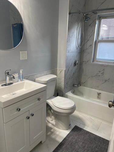 a white bathroom with a sink and a toilet and a tub at Boston Luxury Condo Style Rooms in Boston