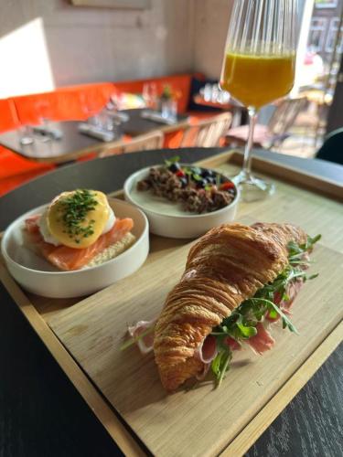 a tray of food with a sandwich and a glass of wine at Bed bij Bistro in Medemblik