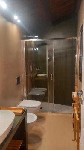 a bathroom with two toilets and a glass shower at La casetta Guest House Oristano in Oristano