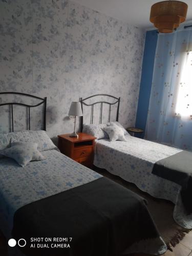 a bedroom with two beds and a table with a lamp at La Buganvilla in Ribadesella
