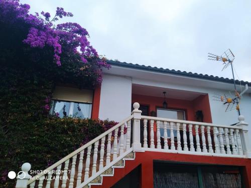 uma casa com uma escada branca e flores roxas em La Buganvilla em Ribadesella