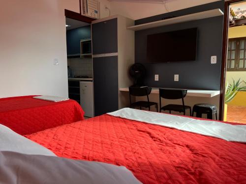 a bedroom with two beds and a flat screen tv at Flat Pé na Areia Cabo Frio in Cabo Frio