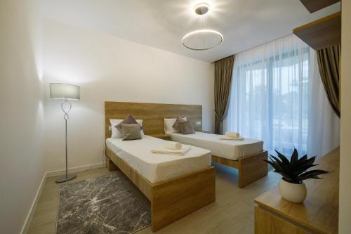 a hotel room with two beds and a window at Purple Luxury Apartment Lake On in Mamaia
