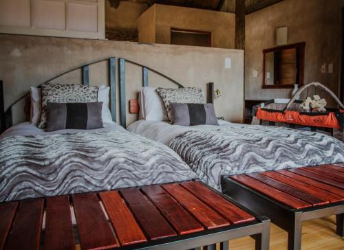 a bedroom with two beds and a wooden bench at Aloe Ridge in Swellendam