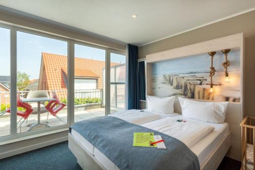 a hotel room with a bed and a large window at Hotel Deichkrone - Familotel Nordsee in Norddeich