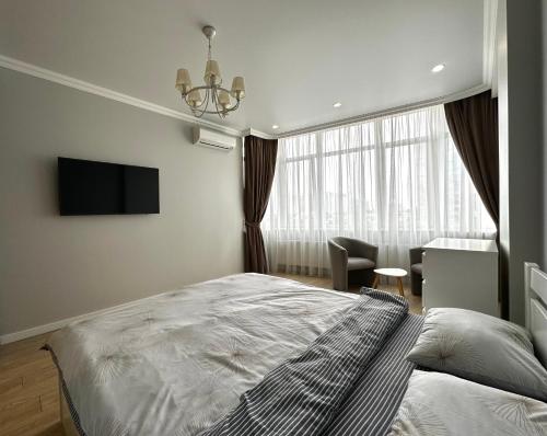 1 dormitorio con 1 cama, TV y silla en Gagarin Plaza Stylish Apartment, en Odessa